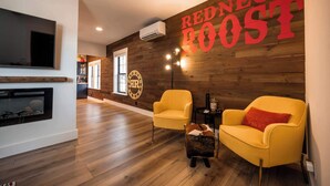 A modern living room with a fireplace, two yellow armchairs, and a wall with 'REDNECK BOOST' signage.