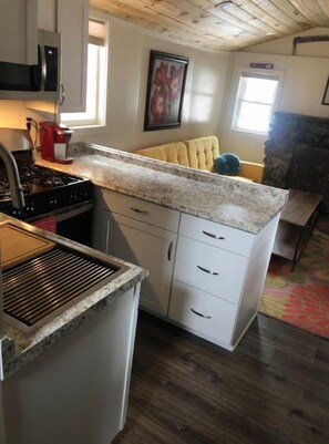 A compact kitchen with a granite countertop, white cabinets, and a built-in stove.