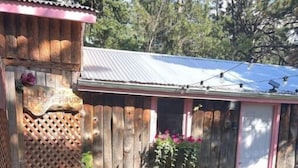 A wooden shed with a corrugated metal roof, a wooden fence, and a garden area with various plants and flowers.