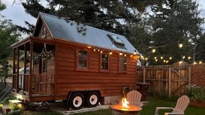 Una cabaña de madera con porche, un hogar y luces colgantes.