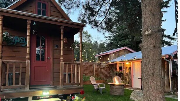 Una cabaña de madera con un porche, un brasero y una pequeña zona de estar al aire libre.