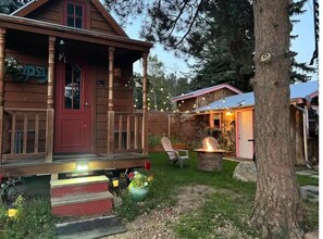 Une cabane en bois dotée d’un porche, d’un foyer et d’un petit espace extérieur aménagé pour s’asseoir.