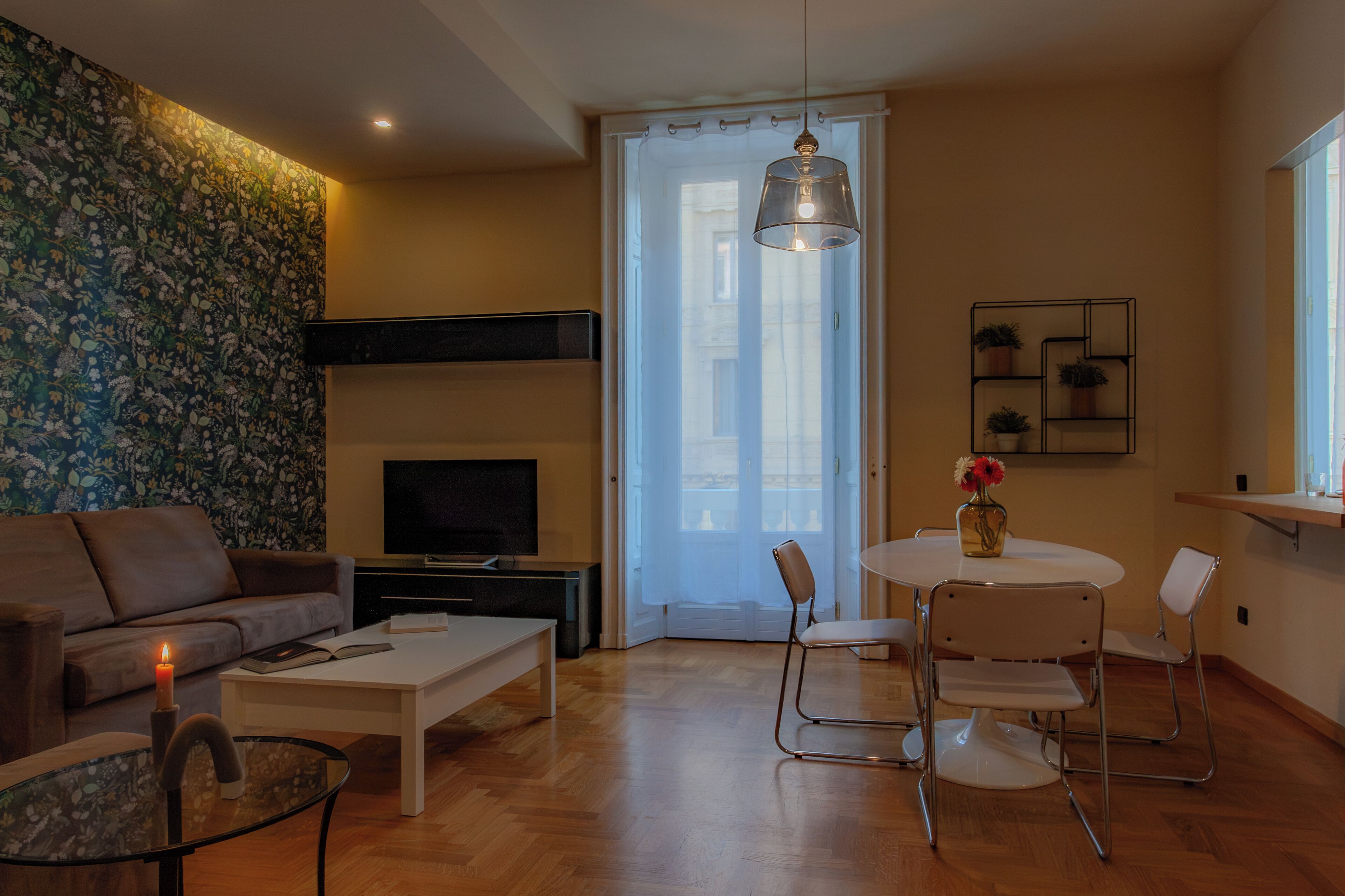 Un salon moderne comprenant un canapé, une table basse, un téléviseur et un coin repas avec des chaises et une table.