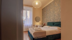 Un dormitorio con cama, mesitas de noche, un espejo redondo y una ventana con cortinas.