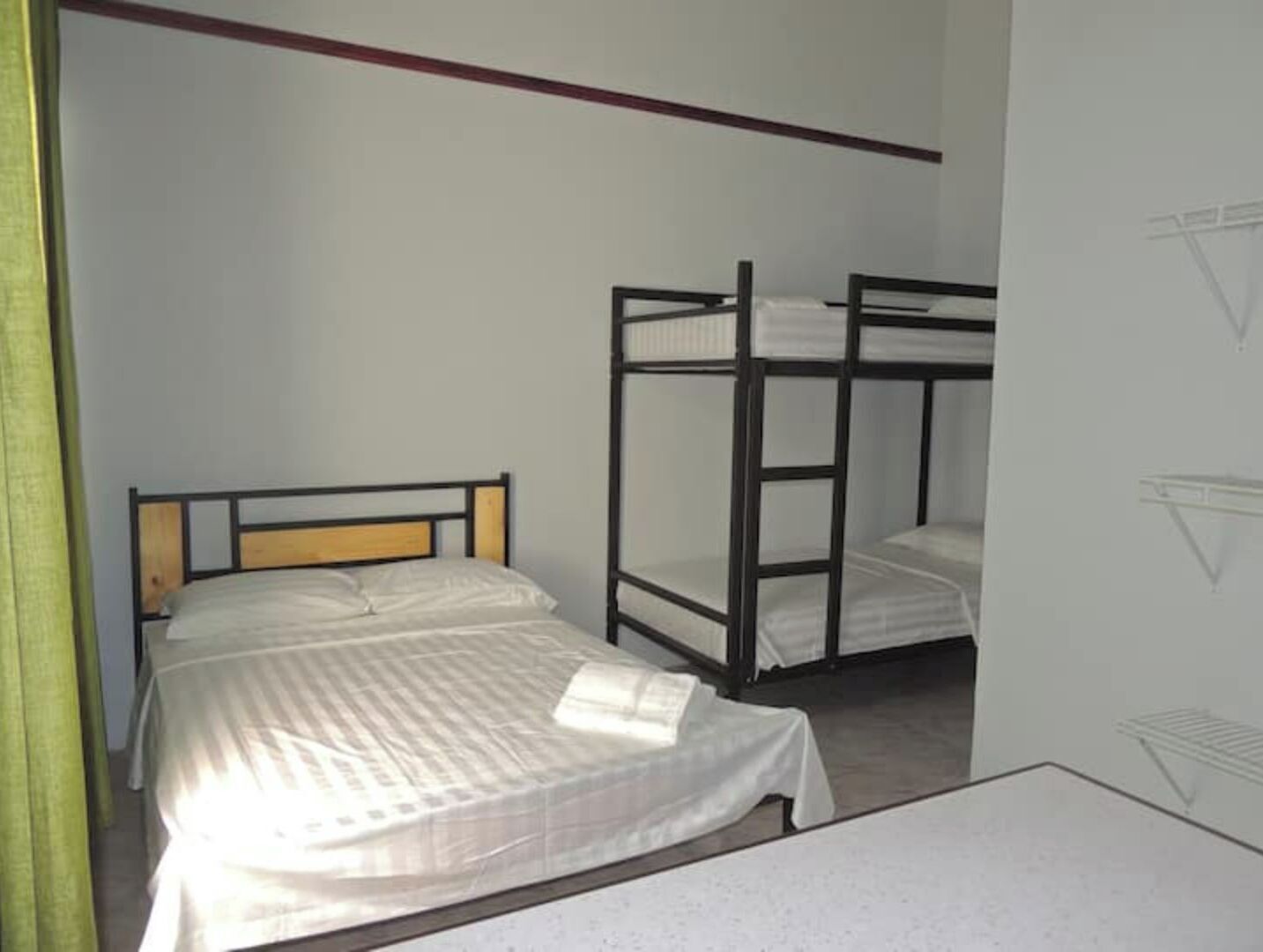 Une chambre de dortoir avec des lits superposés, un lit simple et une petite table.