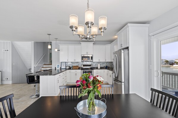Une cuisine moderne avec des meubles blancs, un îlot central et un lustre.
