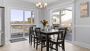 Ein Essbereich mit Tisch und Stühlen, einer Chandelier und Blick ins Freie.