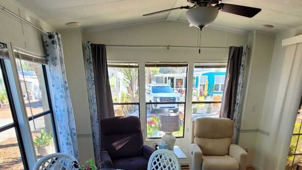 A room with a ceiling fan, a round glass table with chairs, and a view of the outside. - Newly updated in family/pet friendly resort with all the amenities - near beach! (Nokomis)