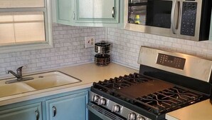 A kitchen with light blue cabinets, a stainless steel stove, a microwave, and a sink. - Newly updated in family/pet friendly resort with all the amenities - near beach! (Nokomis)