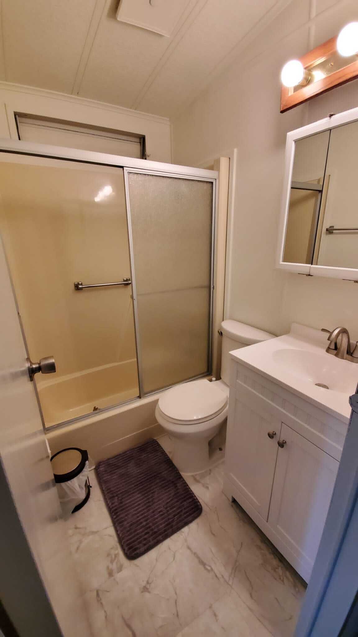 A bathroom with a shower enclosure, toilet, sink, and vanity.