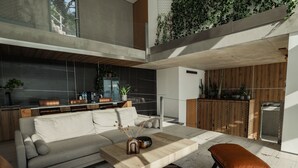 A modern living space with a sofa, coffee table, and ottoman, a kitchen area, and a balcony with plants.
