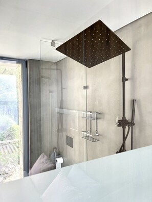 A modern bathroom with a glass shower enclosure, a built-in towel rack, and a visible outdoor view.