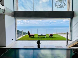 Decoração moderna com uma grande janela de vidro com vista para uma área gramada e o mar.