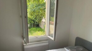Ein Schlafzimmer mit einem Bett, einem Fenster und Blick auf einen Garten.