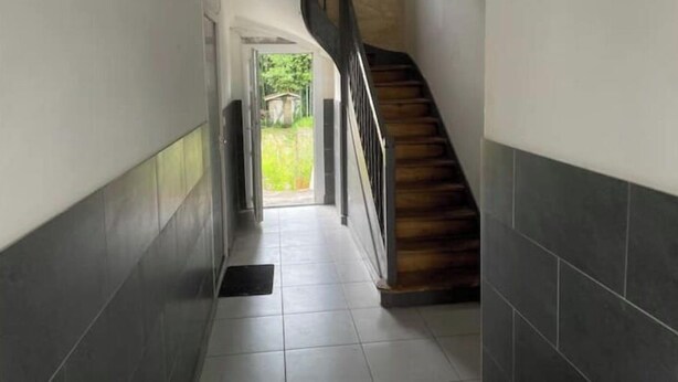 Ein Korridor mit einer Holztreppe, die zu einem Außenbereich führt.