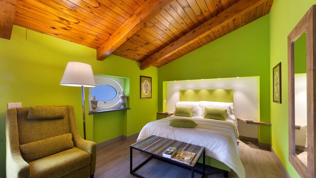 A room with a bed, a chair, a table, and a lamp.