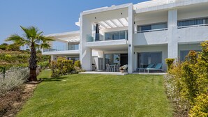 Uma casa moderna de dois andares com telhado plano, grandes janelas e um gramado bem cuidado.