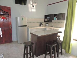 Kitchen area with central island and stools, featuring a refrigerator, microwave, and coffee maker.