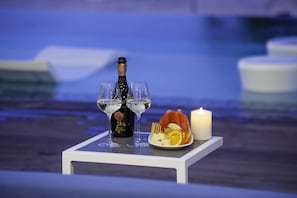A table with a bottle of champagne, two glasses, a plate with cheese and fruit, and a candle. - Club Suites at Rum Point (North Side)