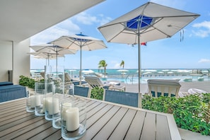 A poolside area with lounge chairs and umbrellas overlooking a pool and ocean view. - Club Suites at Rum Point (North Side)