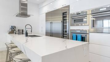 A modern kitchen with a large island, stainless steel appliances, and bar stools.