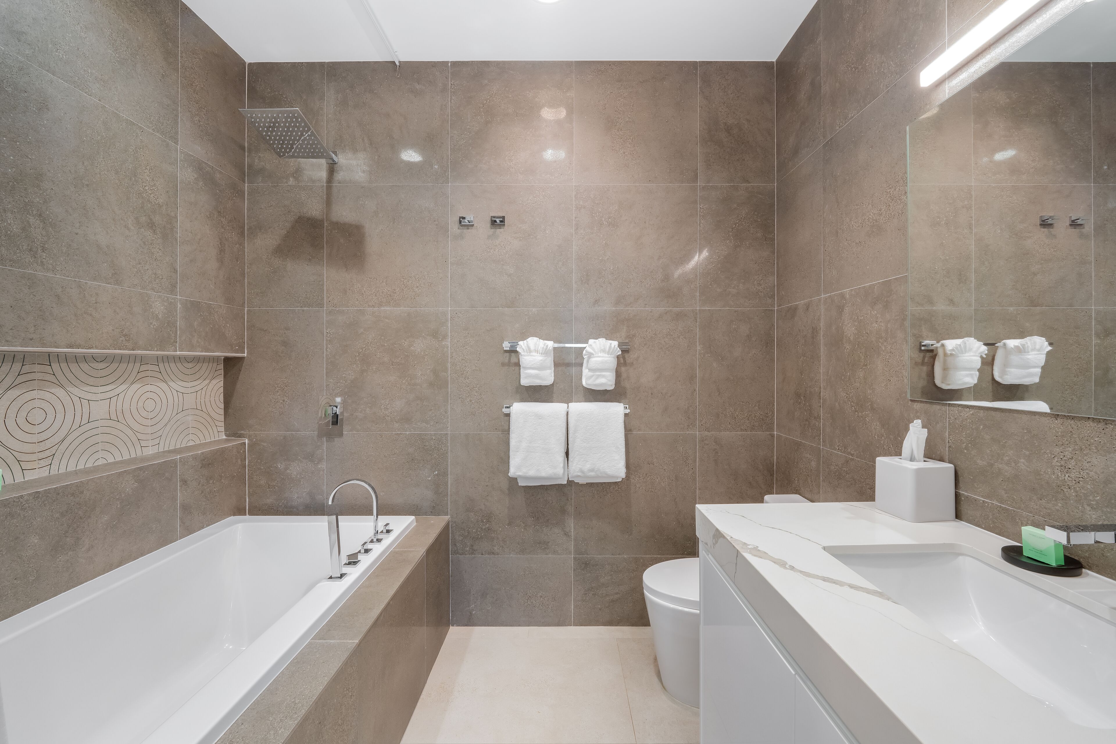 A modern bathroom with a bathtub, toilet, and sink.