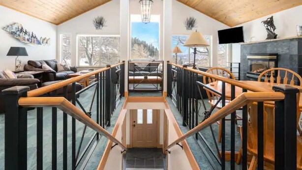 A spacious living area with a wooden staircase, a fireplace, and a view of the outdoors. - Close to town cabin w/Hot Tub in Steamboat Springs (Steamboat Springs)