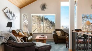 A cozy living room with a large window offering a view of trees and mountains. There are two sofas and a coffee table. - Close to town cabin w/Hot Tub in Steamboat Springs (Steamboat Springs)