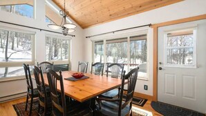 A dining area with a wooden table and chairs, large windows with a view of trees, and a white door. - Close to town cabin w/Hot Tub in Steamboat Springs (Steamboat Springs)