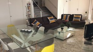 Ein modernes Wohnzimmer mit einem Glastisch, zwei Sofas und einer Treppe zu einer weiteren Ebene.