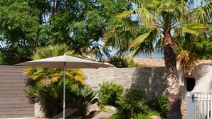 Een terras met lounge fauteuils, een grote parasol en een palmboom.