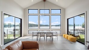 A spacious room with large windows, a dining area, and a leather sofa. - Lavish Lake Getaway W/180* Views+ Boat Dock (Knoxville)