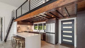 A modern kitchen with a central island, stainless steel appliances, and a wooden ceiling. - Lavish Lake Getaway W/180* Views+ Boat Dock (Knoxville)