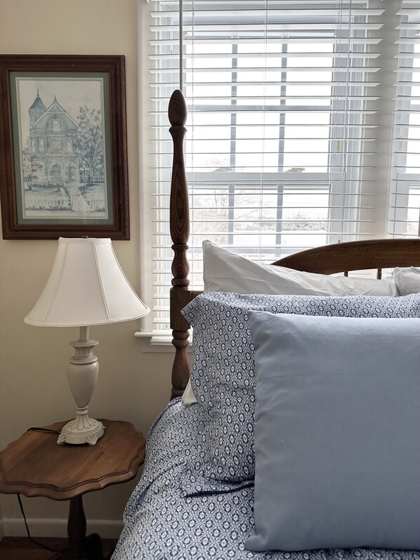 A bedroom with a wooden bed frame, patterned bedding, a bedside table with a lamp, and a framed picture on the wall. - Updated 4BR close to downtown Chatham, Beaches, Bike Path & Tennis Pickleball (Chatham)