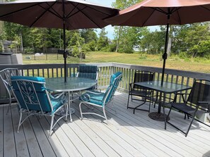Une terrasse dotée de mobilier d’extérieur, comprenant une table et des chaises, ainsi que deux parasols.