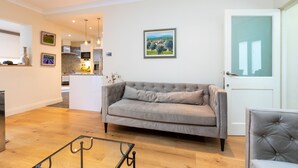 A modern living room with a grey sofa, a glass coffee table, and a door with frosted glass panels. - Modern and Bright 3 Bedroom House in Paddington (London)
