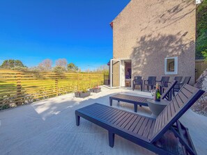 A patio with outdoor furniture, a bottle of champagne, and a view of a rural landscape.