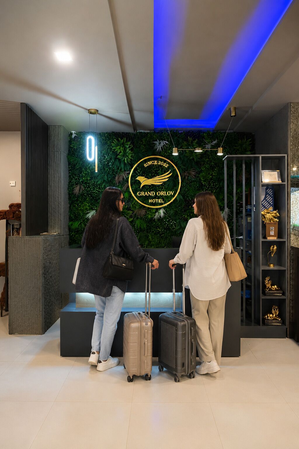 Een receptie met het logo van Grand Orlov Hotel, een receptiebalie en een wand met beplanting.