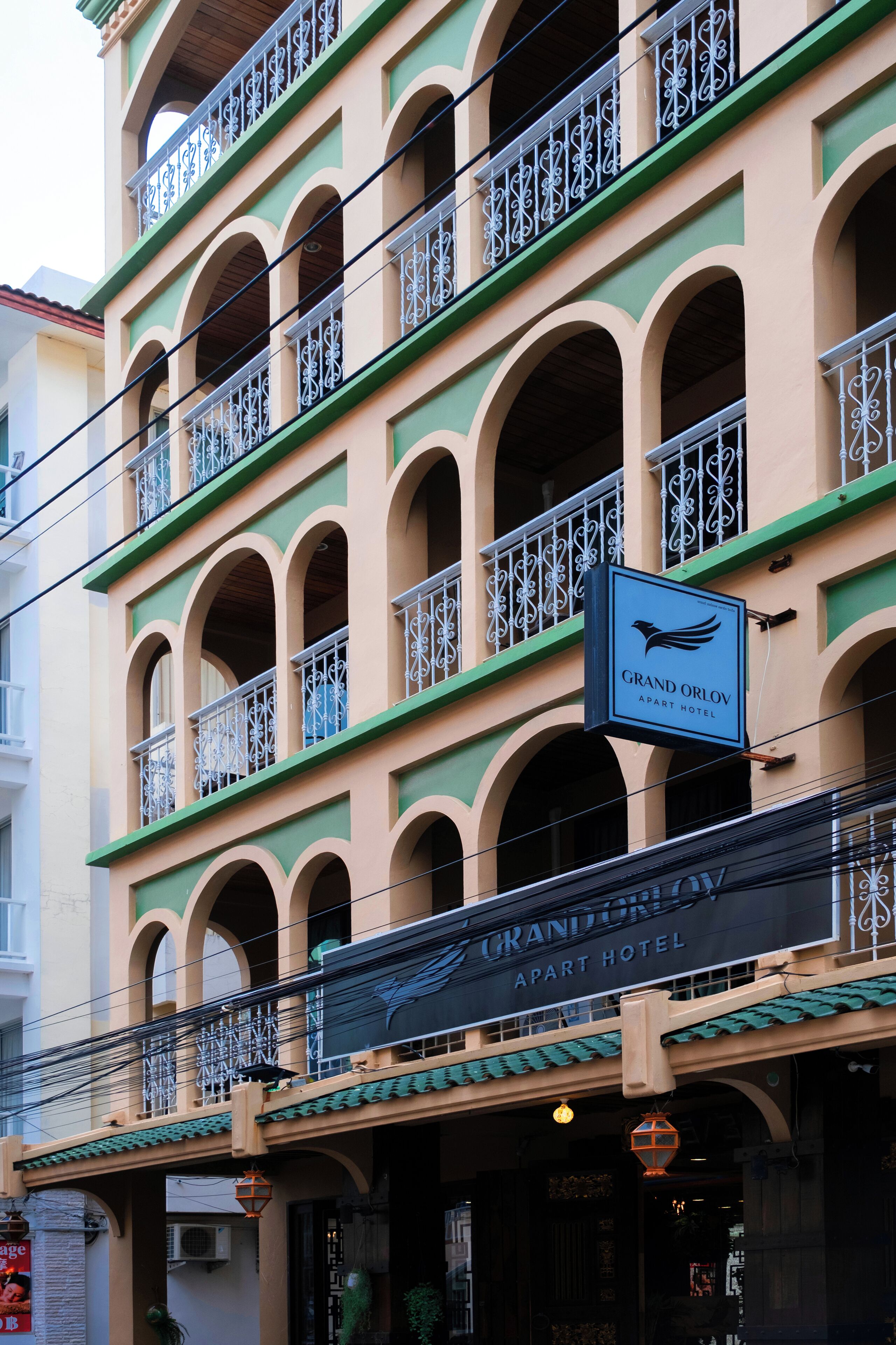 A multi-story building with balconies and a sign for the Grand Orlov Apartment Hotel.