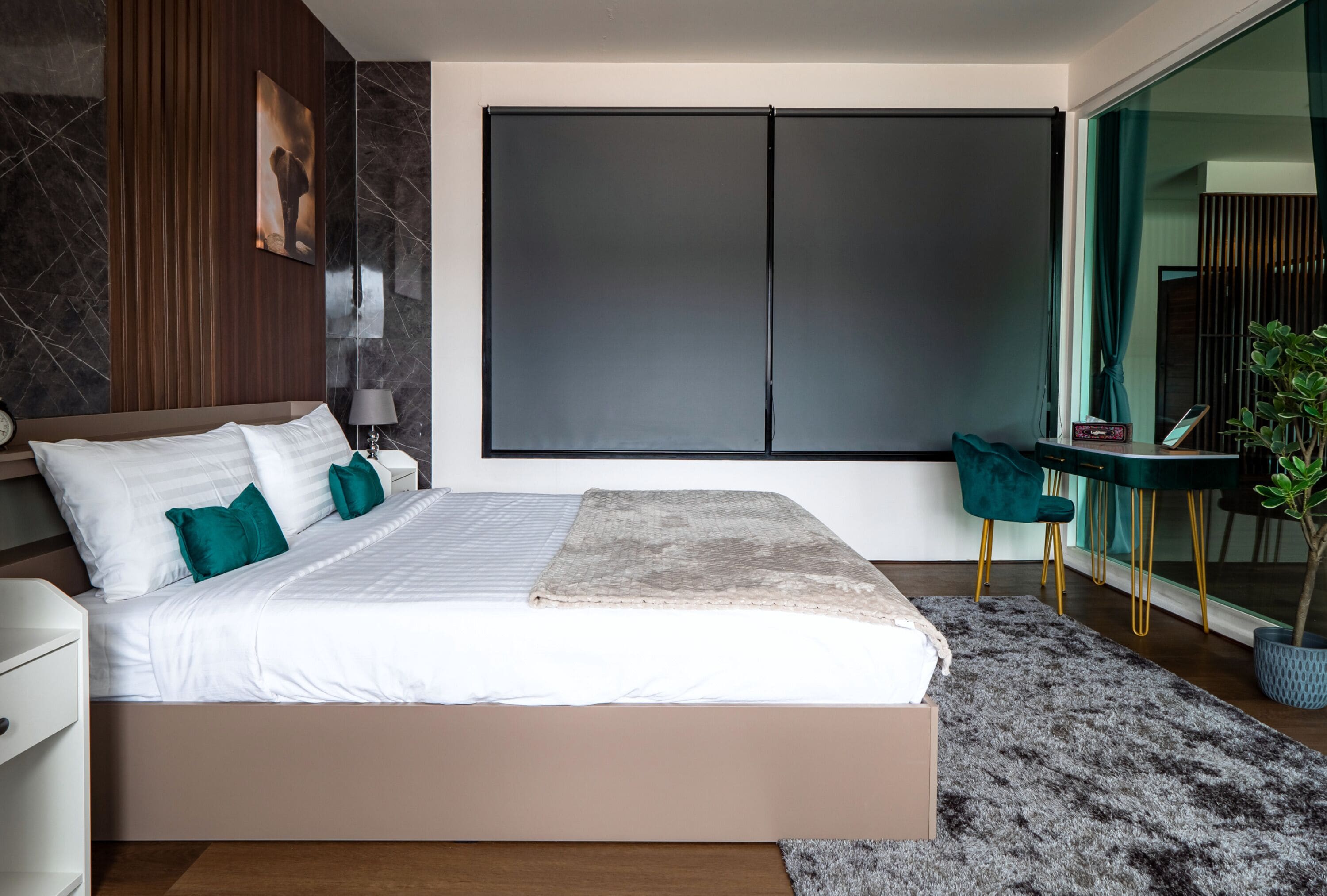 A modern bedroom with a large bed, a desk, and a chair.