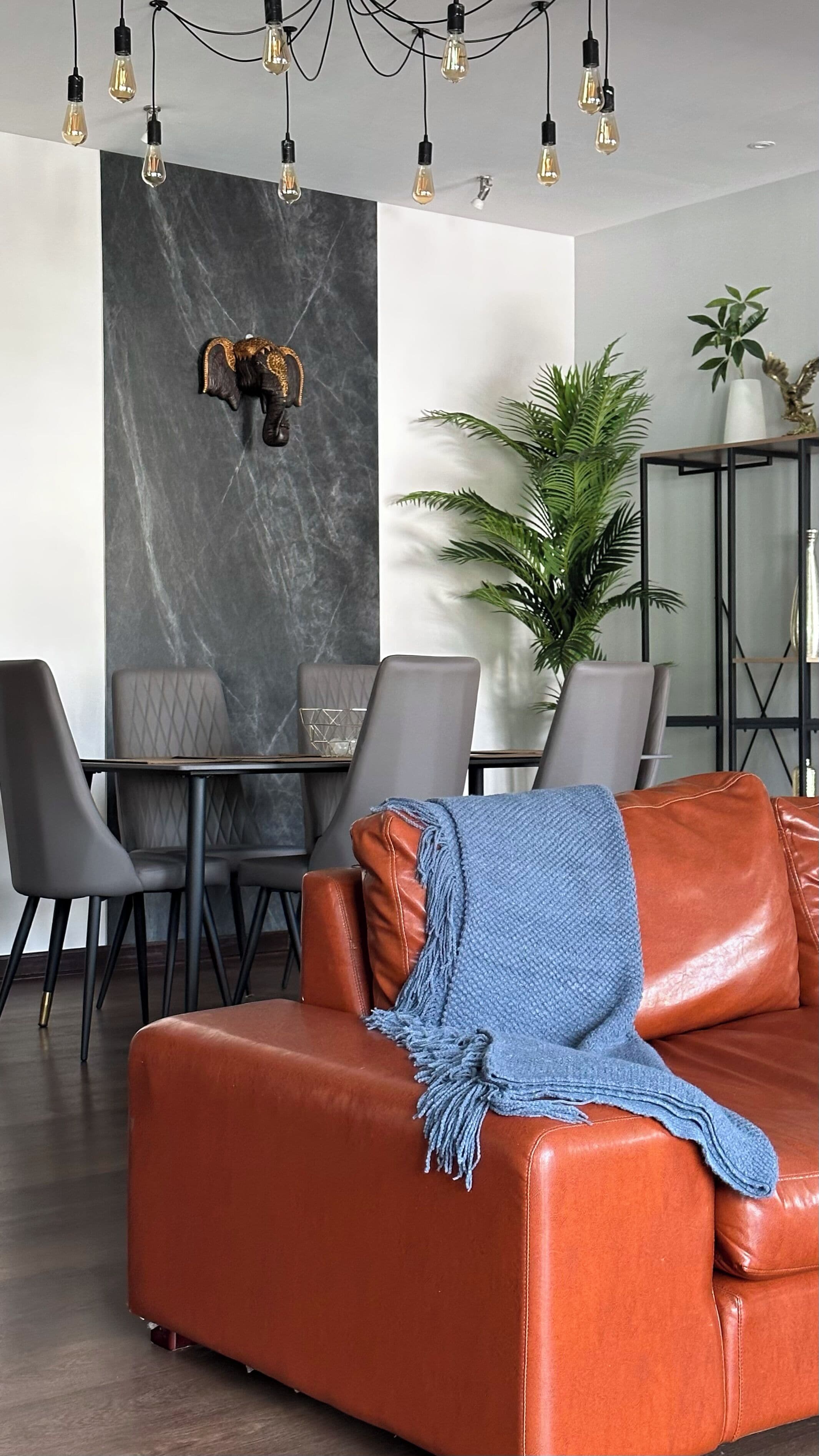 A modern dining area with a marble wall, a decorative elephant head, and a dining table with chairs.
