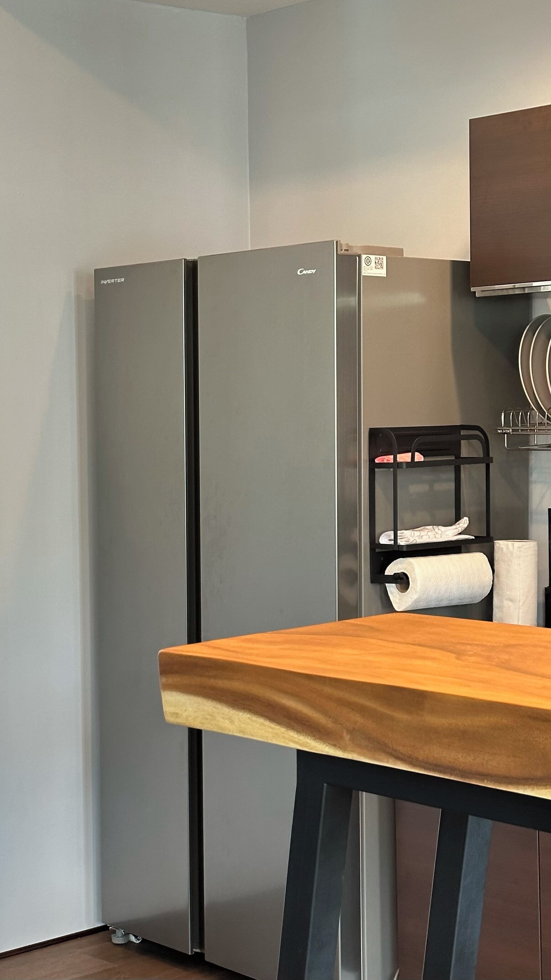 Una cocina con dos refrigeradores de acero inoxidable, una mesa de madera y una silla negra con una toalla.