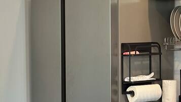 Una cocina con dos refrigeradores de acero inoxidable, una mesa de madera y una silla negra con una toalla.