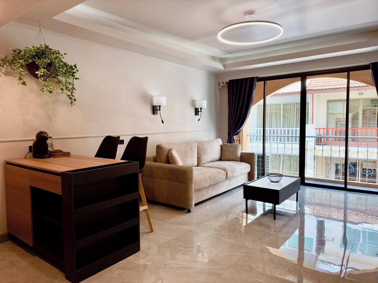 A modern living room with a sofa, a coffee table, and a desk with a hanging plant.