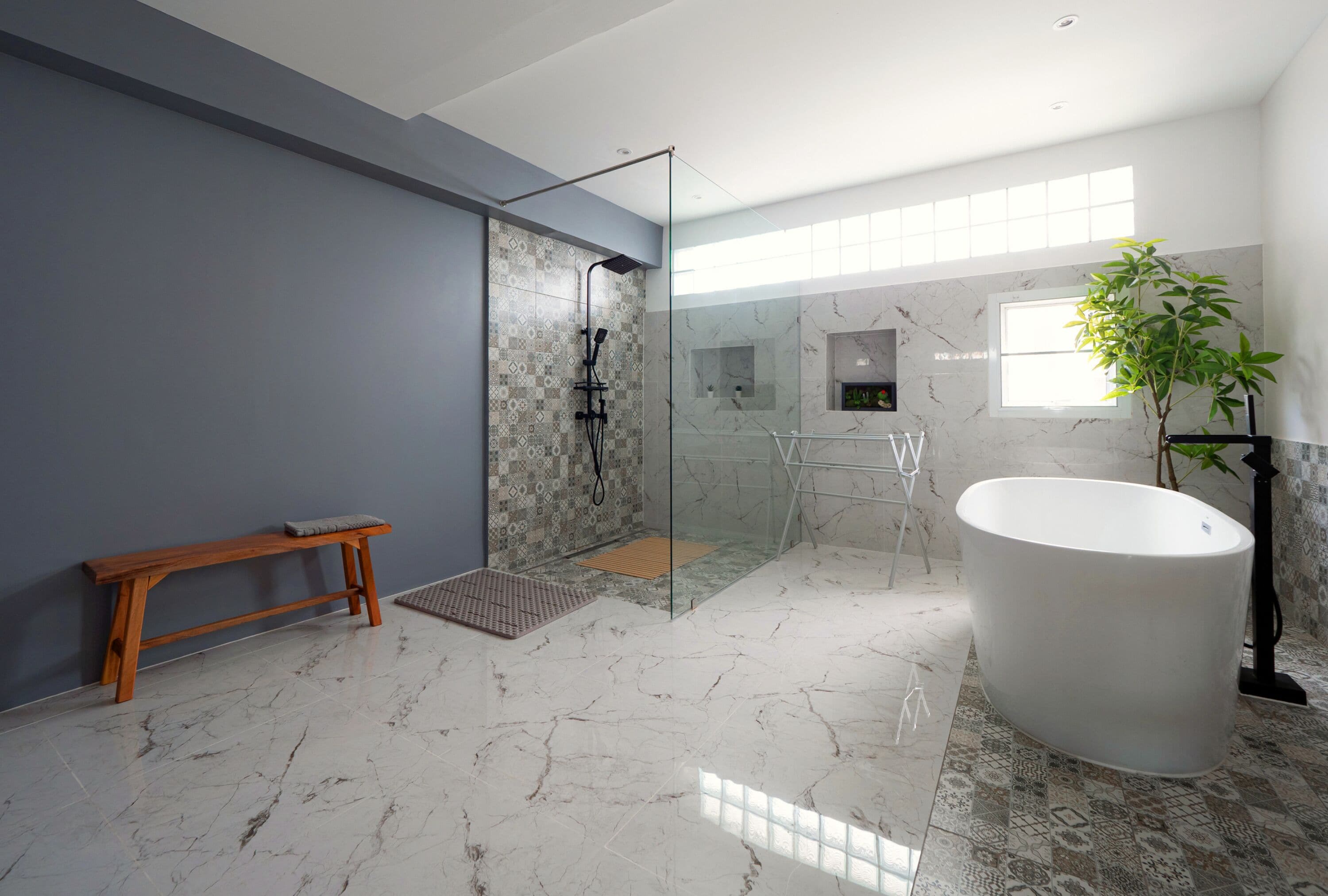 A modern bathroom with a glass-enclosed shower, a large bathtub, and a bench.