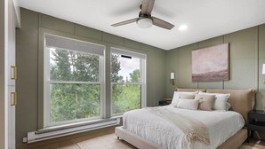 A bedroom with a large bed, a ceiling fan, and a window with a view of trees. - Resort-Style Brian Head Condo Near Slopes! (Brian Head)