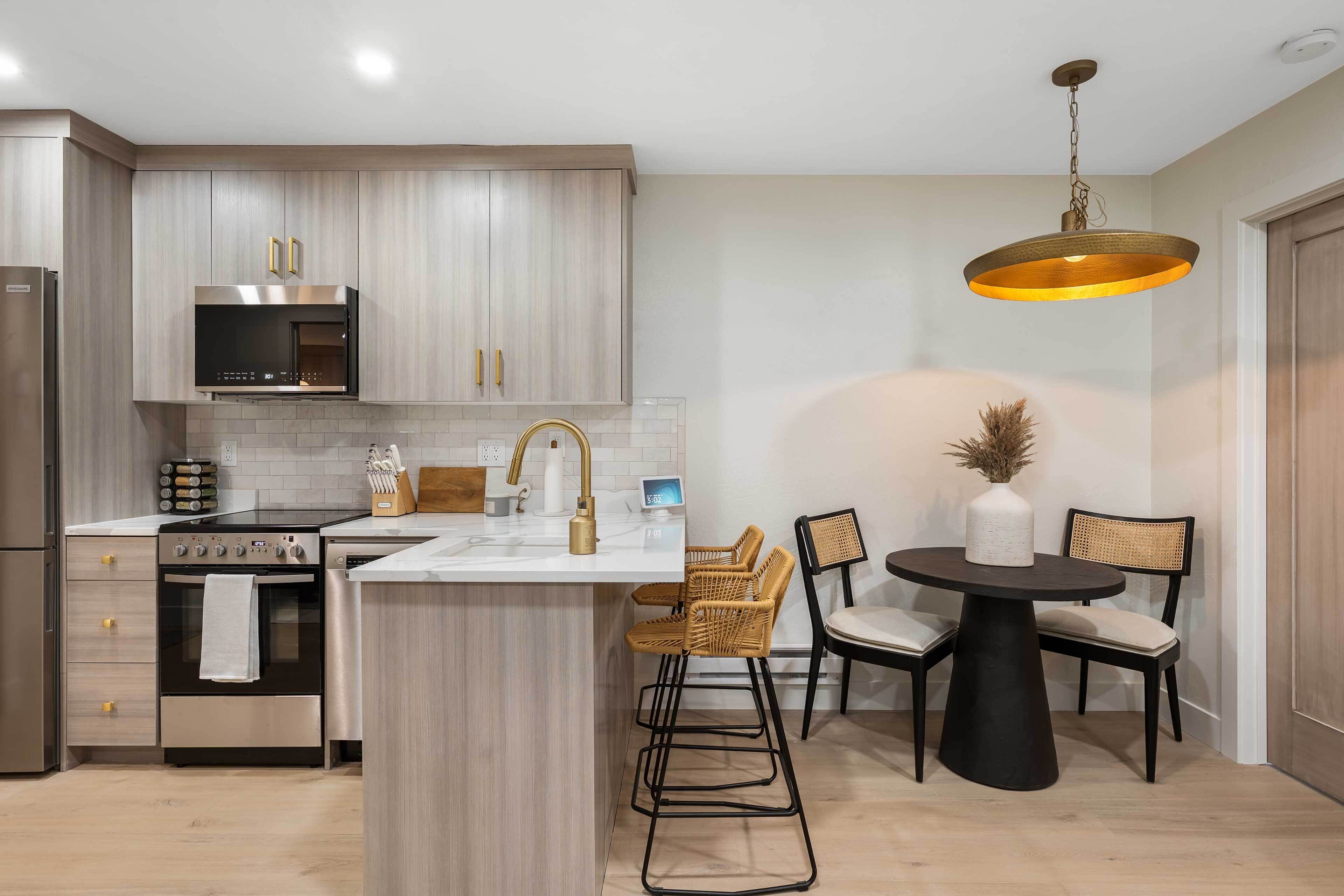 Een moderne keuken met roestvrijstalen apparatuur, een centraal eiland en een eetgedeelte met een ronde tafel en stoelen.