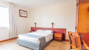 Ein Hotelzimmer mit Bett, Nachttischen, Schreibtisch und Stuhl.