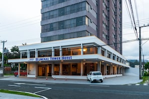 Un hotel moderno con fachada plana, amplias ventanas y un letrero llamativo que dice "Blumenau Tower Hotel".