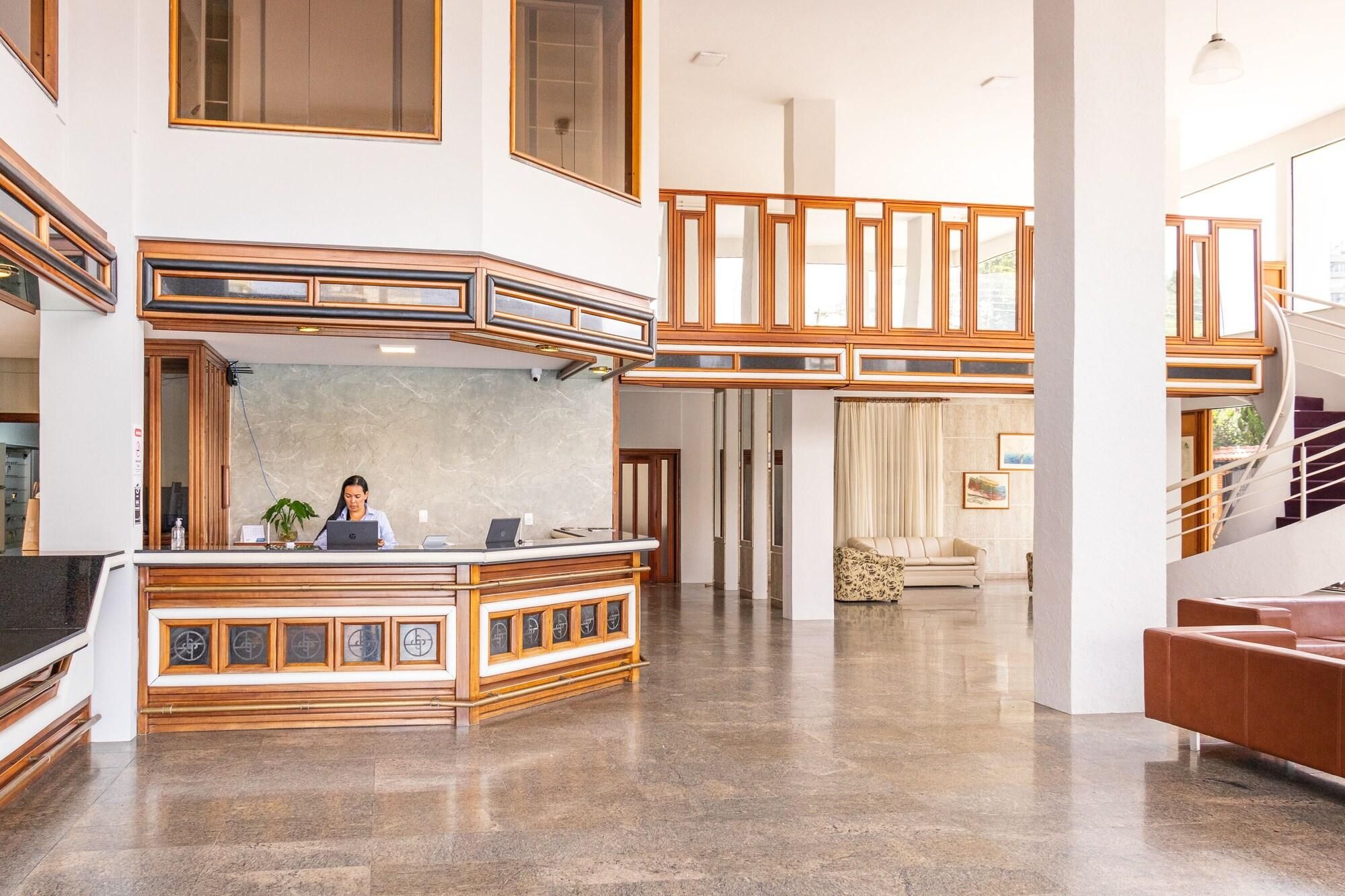 Un vestíbulo amplio con mostrador de recepción, una escalera y una zona de estar.
